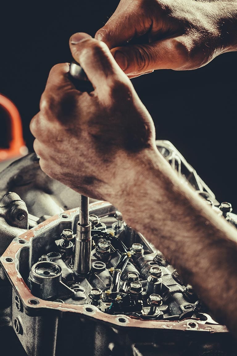 Hydra-Tech Transmissions - close-up of hands working on a transmission with a dark background